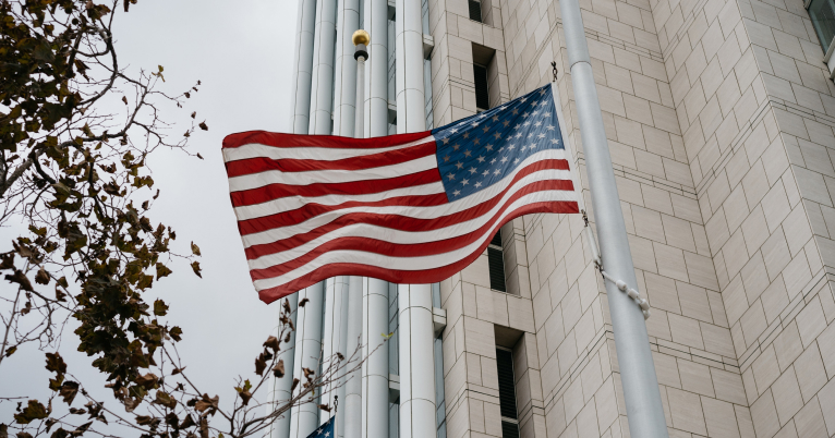 An American flag outside of a government building, blowing in the wind
