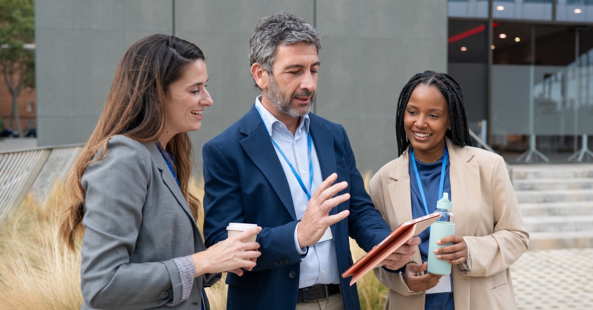 Three colleagues looking at tablet device smiling.
